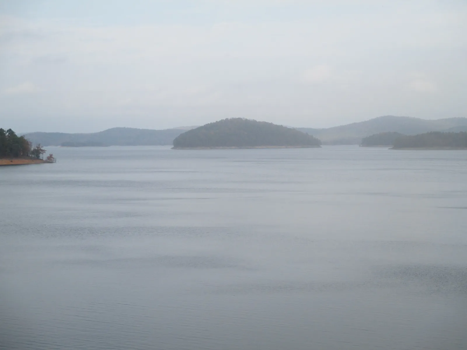 Misty panorama of Broken Bow Lake with a forested island