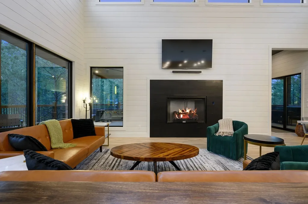 Living room at The Arcadia with camel leather sofas, emerald green chairs, linear fireplace, and shiplap walls
