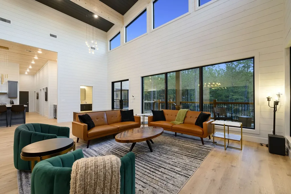 Double-height great room at The Arcadia with camel leather sofas, emerald green accent chairs, and fireplace