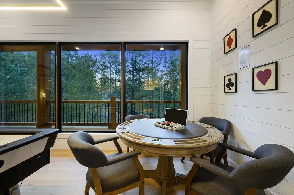 Poker table with gray upholstered chairs and playing card suit wall art on covered porch at The Arcadia