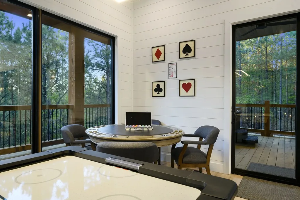Poker room at The Arcadia with round table, card suit artwork, and views into the forest
