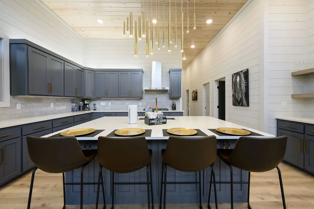 Kitchen island at The Arcadia with bar stools, gray cabinetry, and vaulted wood ceiling with pendant lights