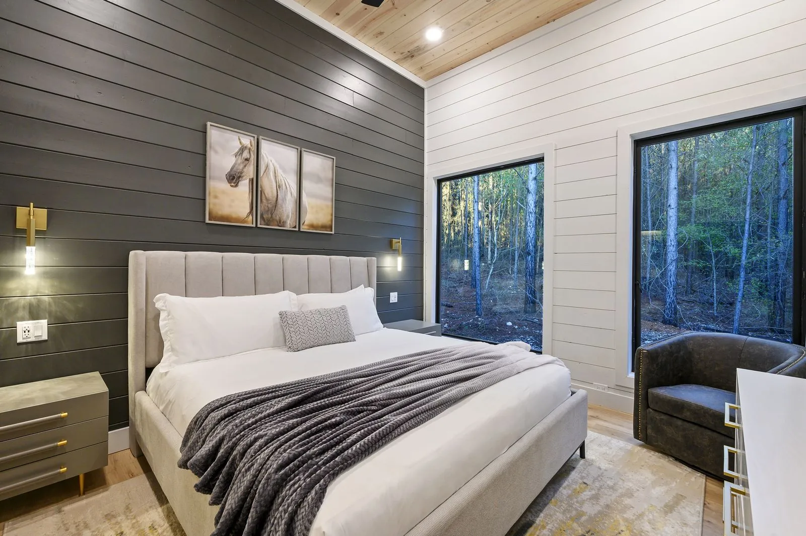 King bedroom at The Arcadia with navy accent bedding, wood ceiling, and wall-mounted TV