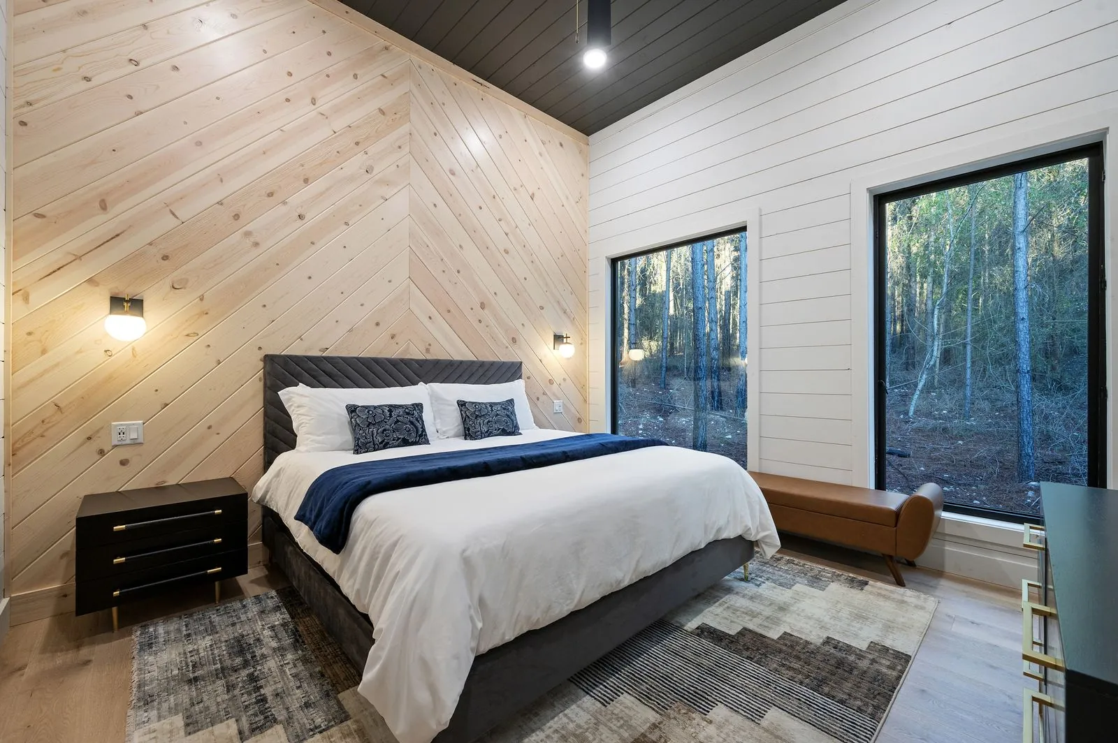 King bedroom at The Arcadia with black and white striped rug, shiplap walls, and blue navy bedding