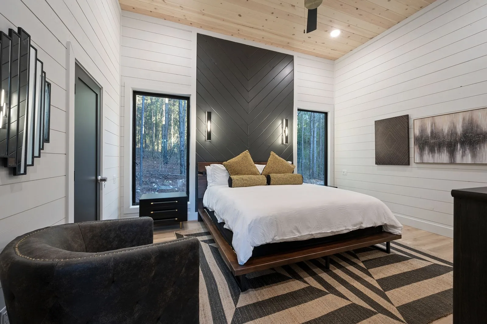 King bedroom at The Arcadia with navy blue throw, horse artwork triptych, and upholstered headboard