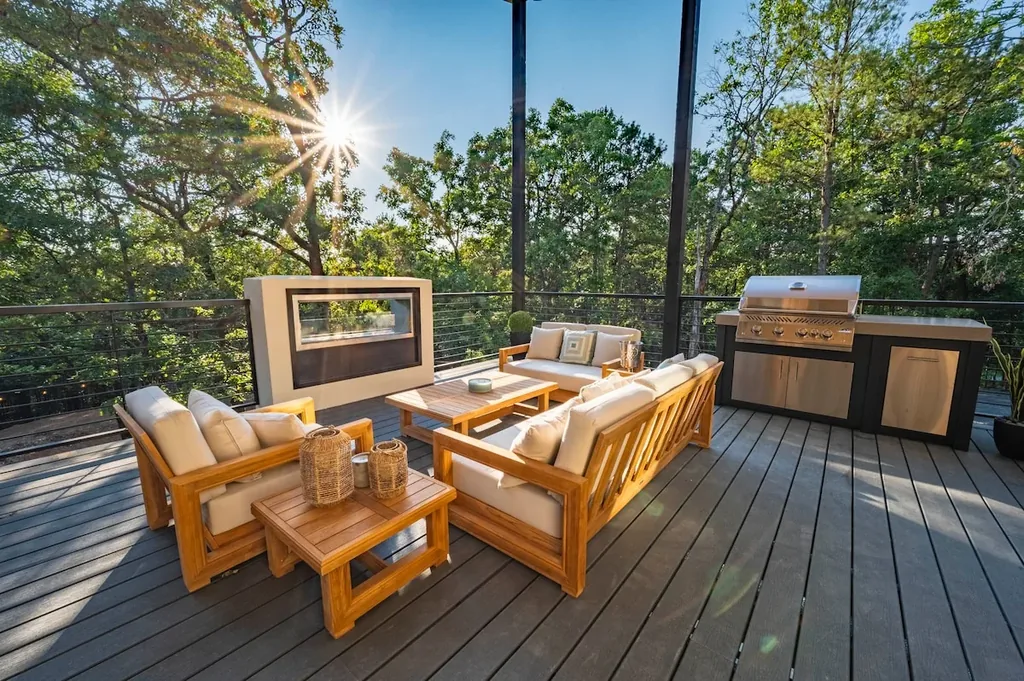 Covered outdoor lounge, fireplace, dining area, and grill at The Aroha