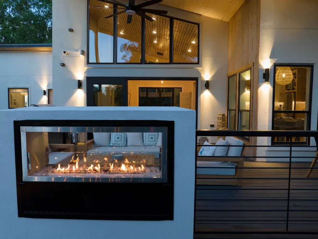See-through deck fireplace illuminated at dusk at The Aroha