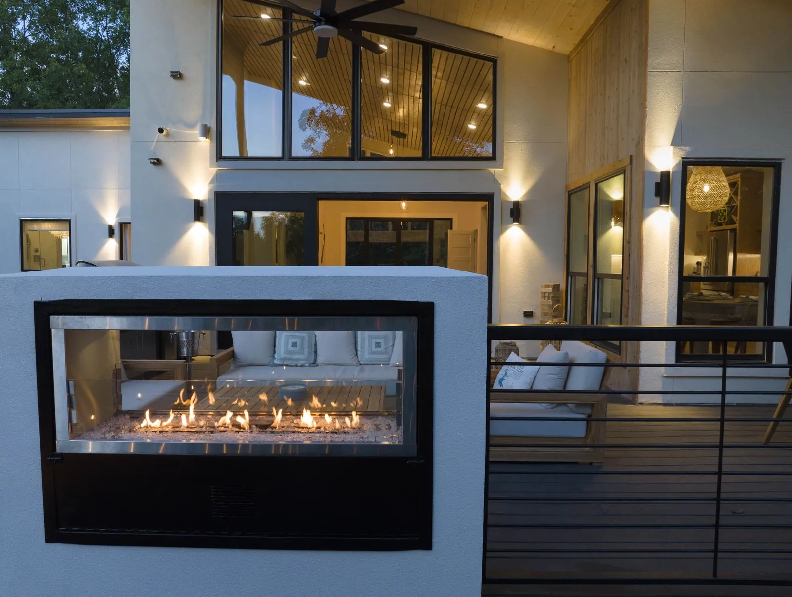 Front exterior of The Aroha at twilight showcasing the dual-sided linear fireplace and modern glass architecture