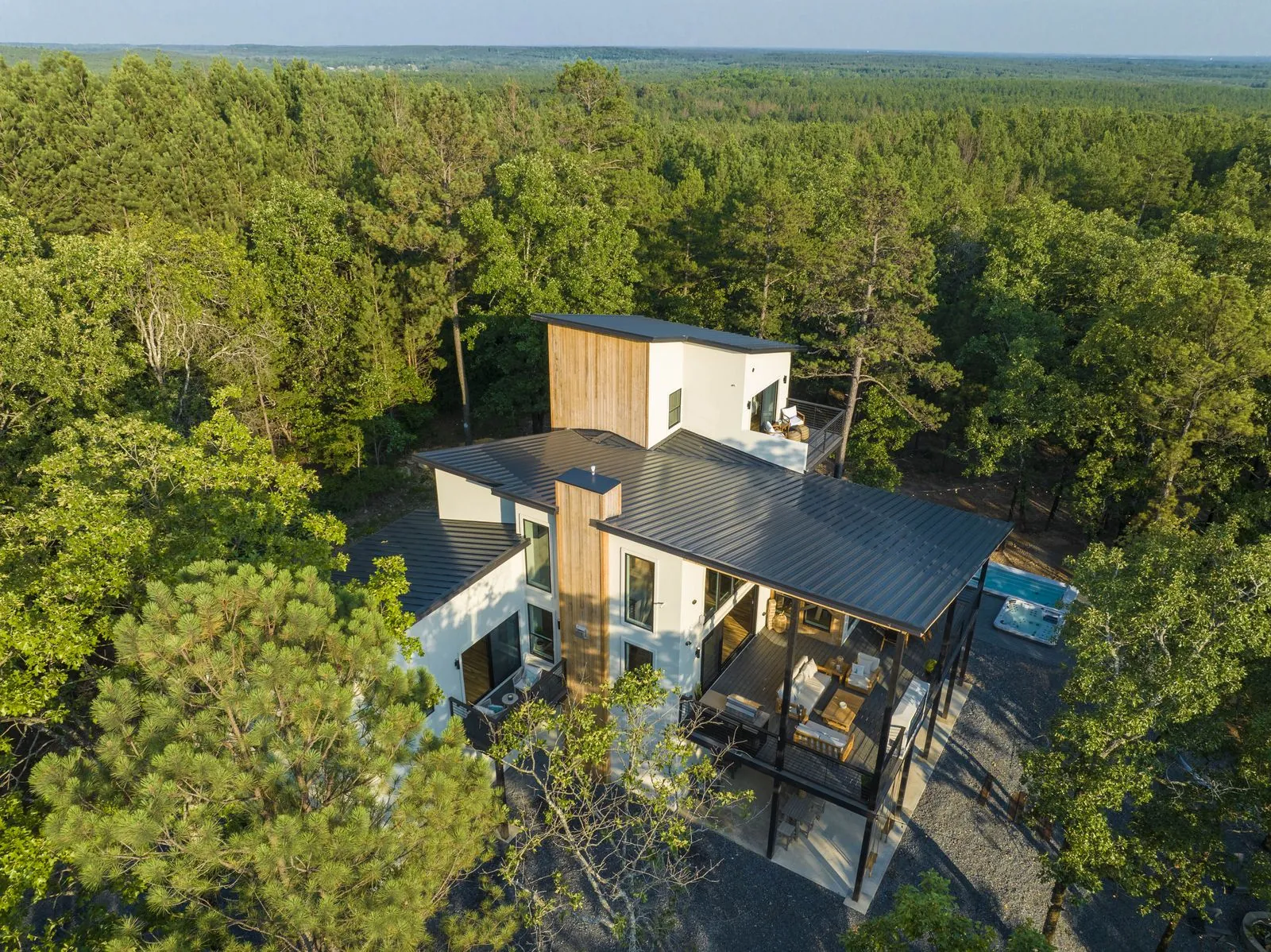 Aerial view of The Aroha modern cabin nestled among tall trees in the Broken Bow forest