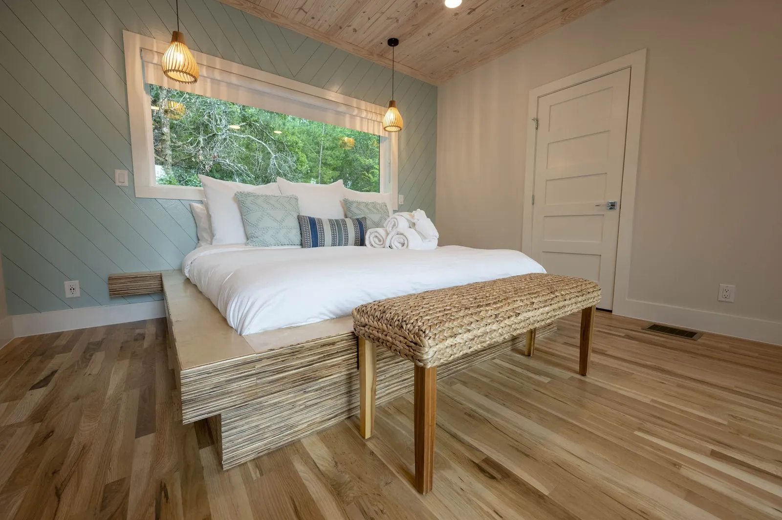 Bedroom at The Aroha with a blue accent wall and forest views