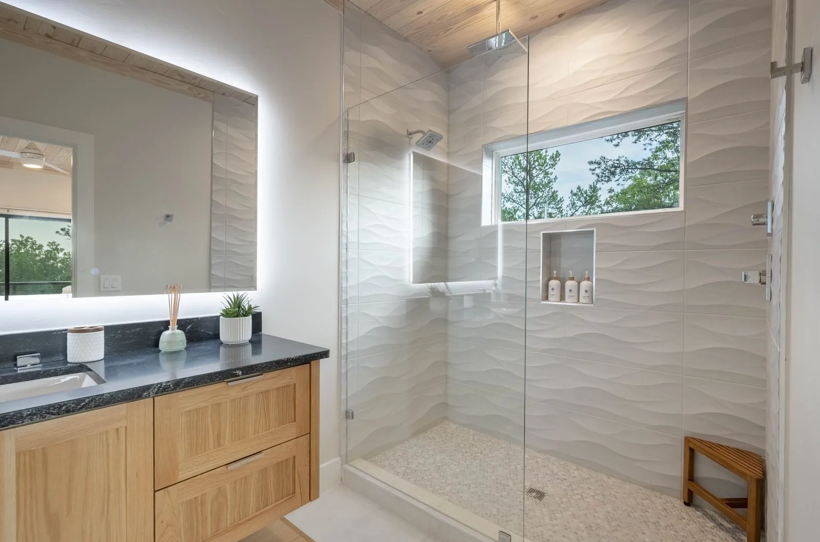 Small bathroom at The Aroha with round mirror, vessel sink, and wood slat vanity shelf