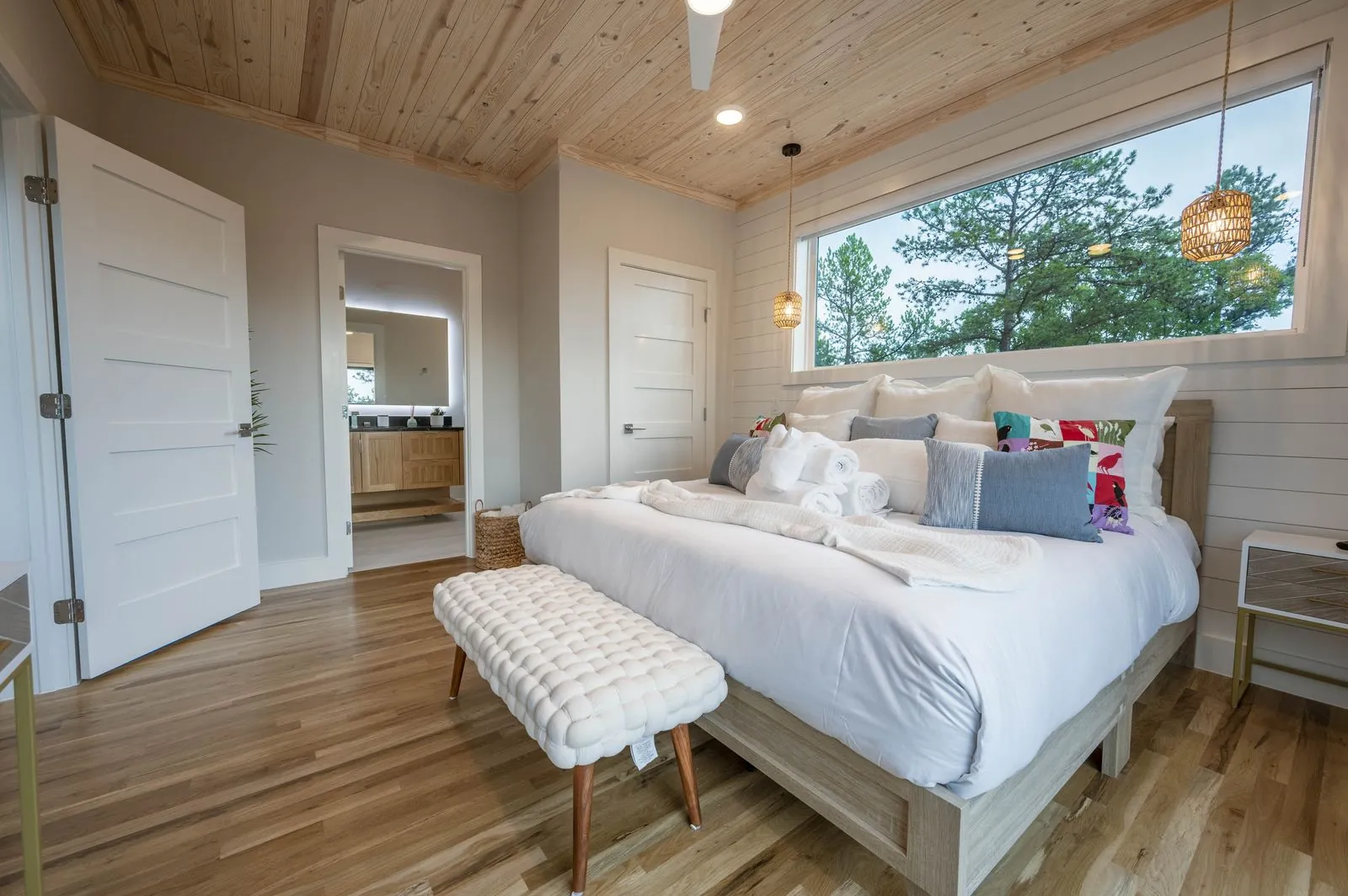 King bedroom at The Aroha with white bedding, blue accent pillows, and glass door to balcony