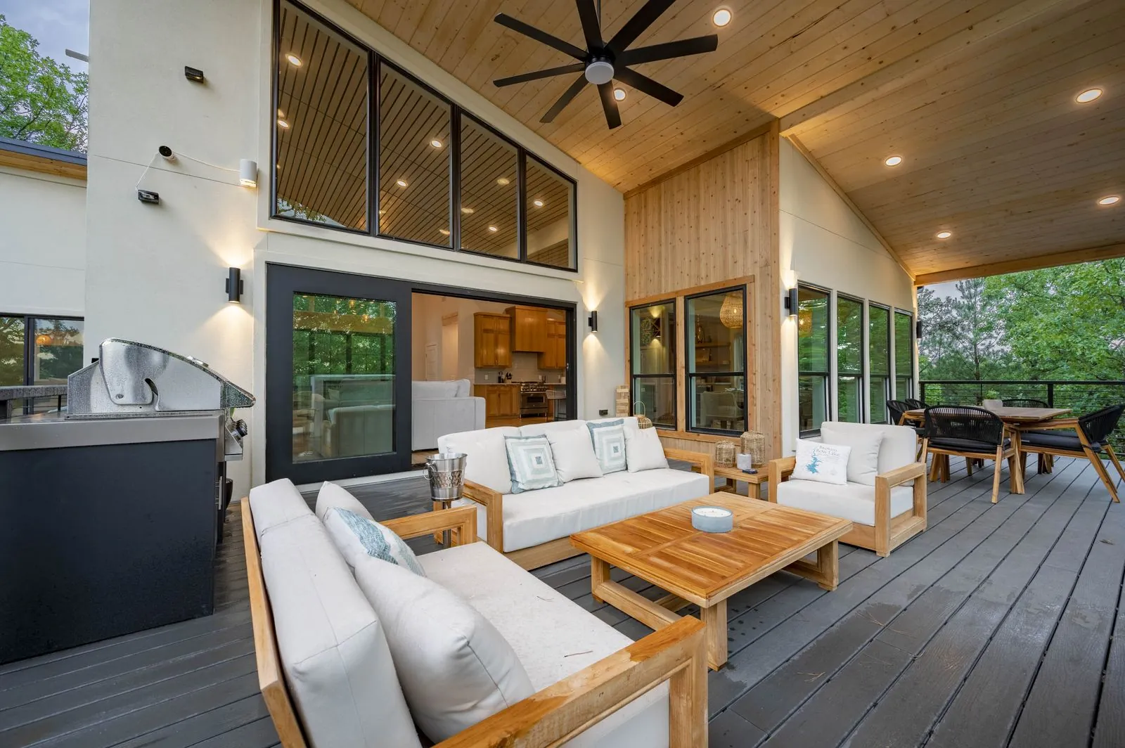Glass walk-in shower at The Aroha with wave tile walls, wooden bench, and forest-view window