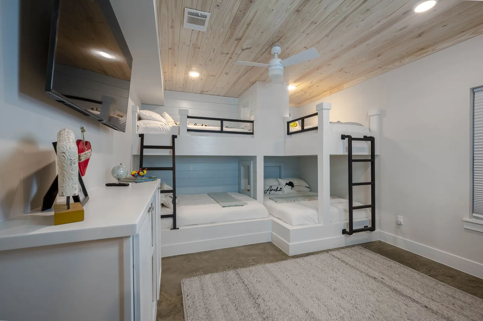 Bedroom at The Aroha with king bed, colorful accent pillows, wood ceiling, and pendant lights