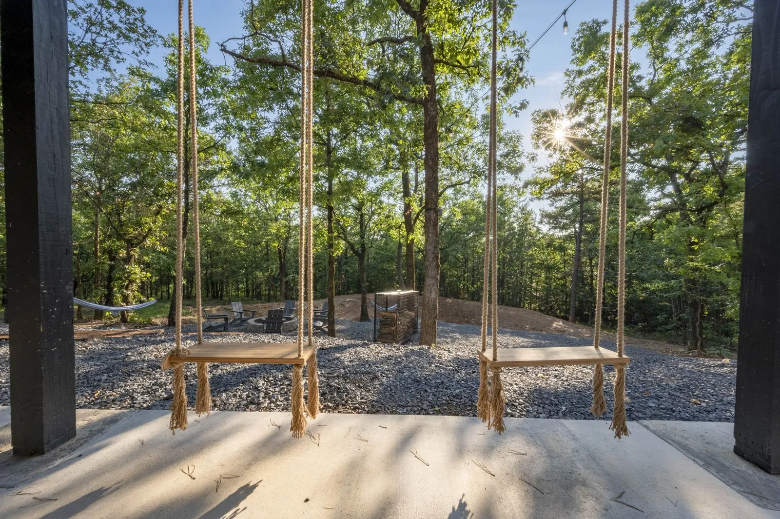 Fire pit area at The Aroha with Adirondack chairs and multi-level cabin glowing at dusk in background