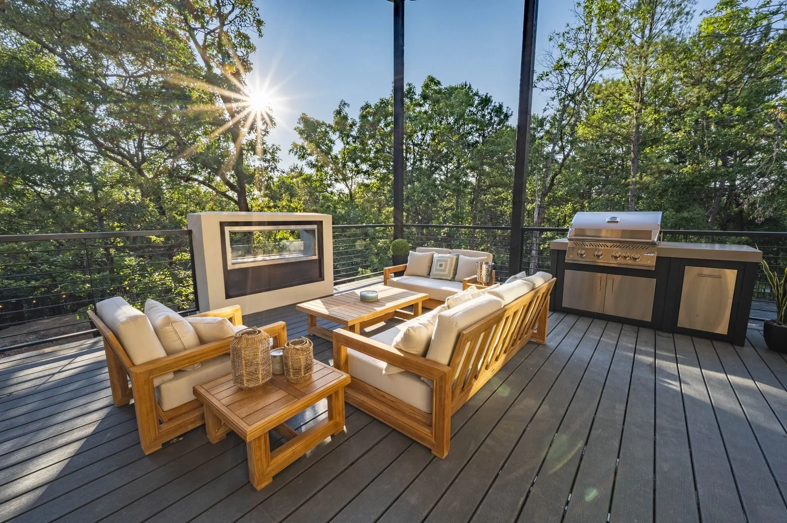 Elevated dining deck at The Aroha with wood table, black woven chairs, and treetop views at sunset