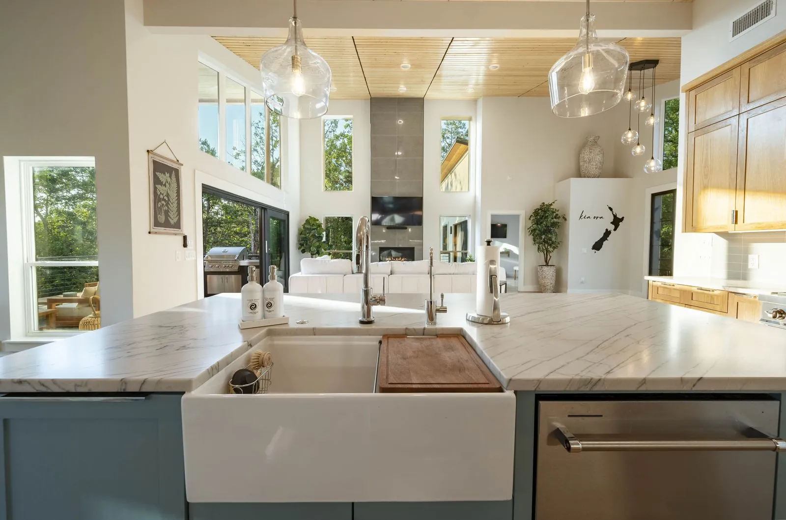 Kitchen at The Aroha with blue island, wood cabinets, and open sightline to dining room