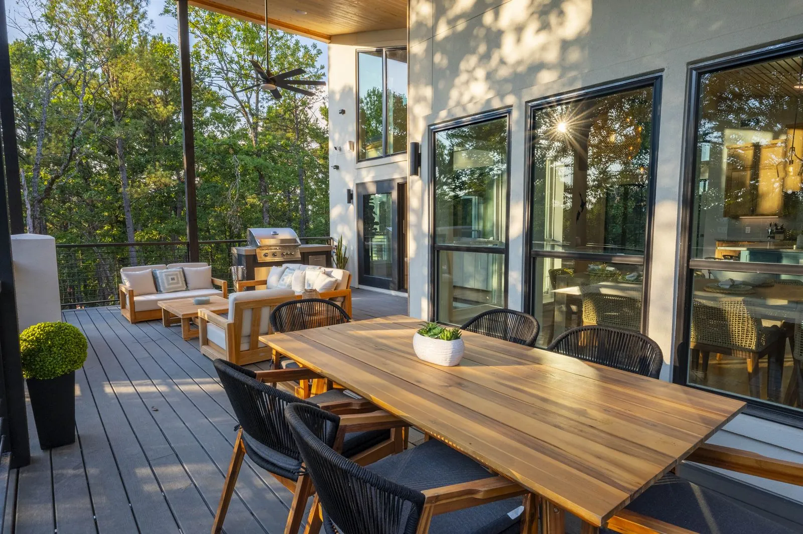 Covered deck dining table at The Aroha set for dinner with candles and treetop views at dusk