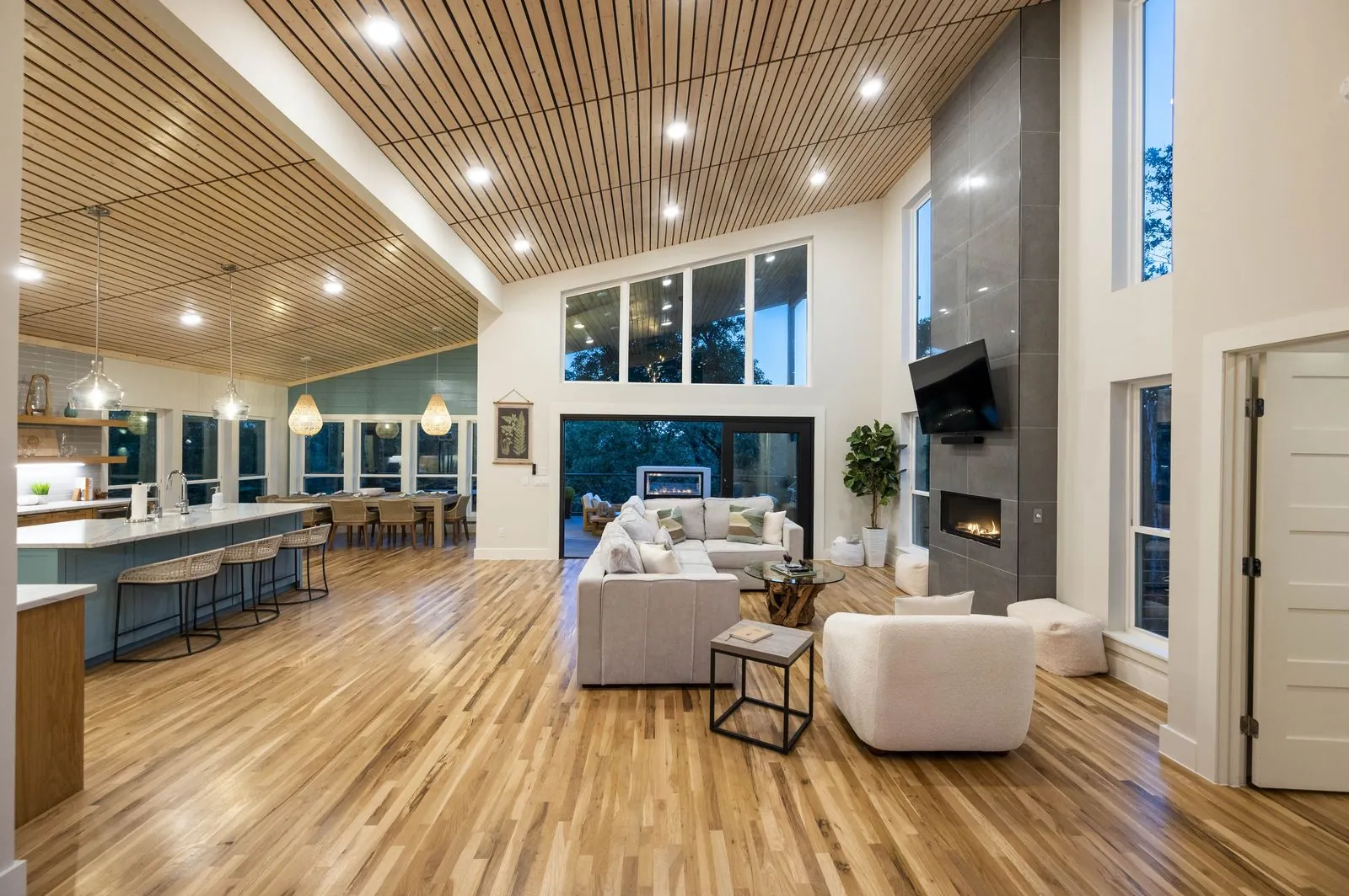 Upper deck at The Aroha at dusk with string lights and panoramic forest views through cable railing