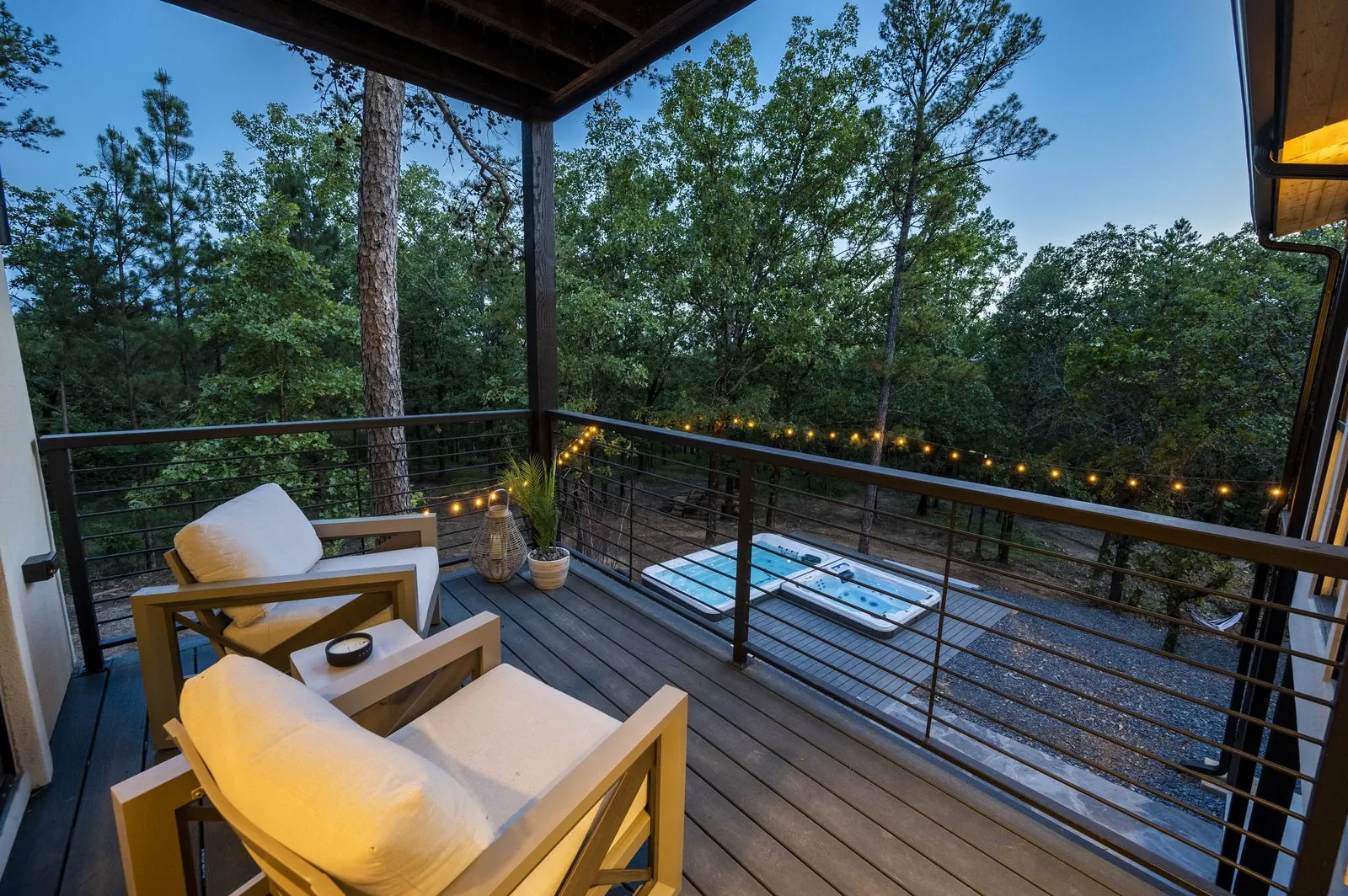 Hot tub on lower deck at The Aroha with string lights and striped loungers at twilight