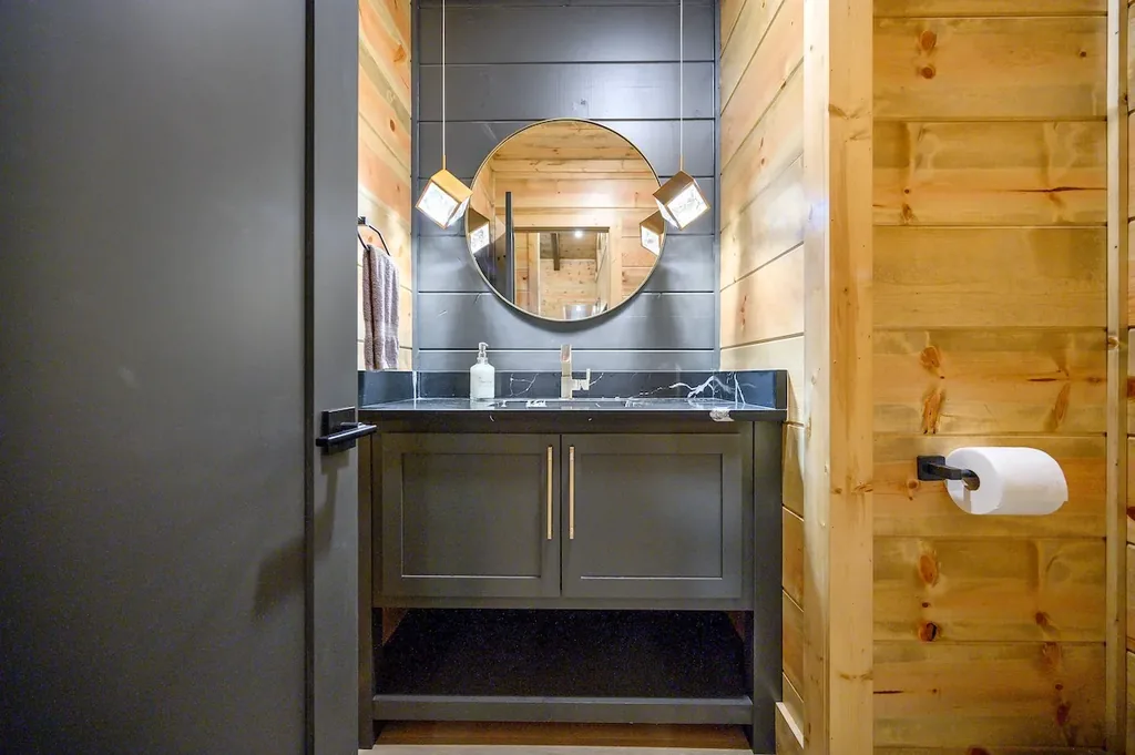 Half bathroom with black vanity and round mirror
