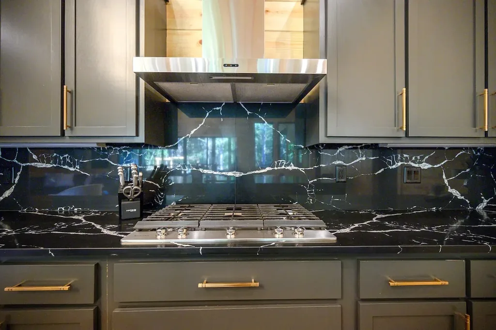 Gas cooktop and stainless hood set in black marble