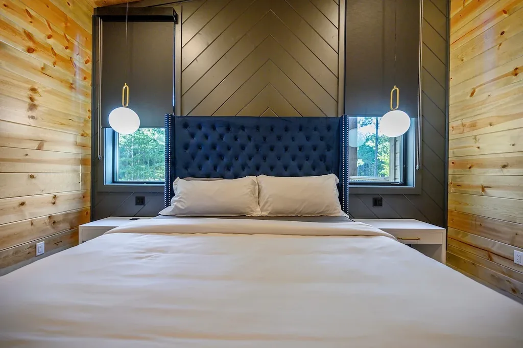 King Bedroom 1 with blue tufted headboard and pendant lights