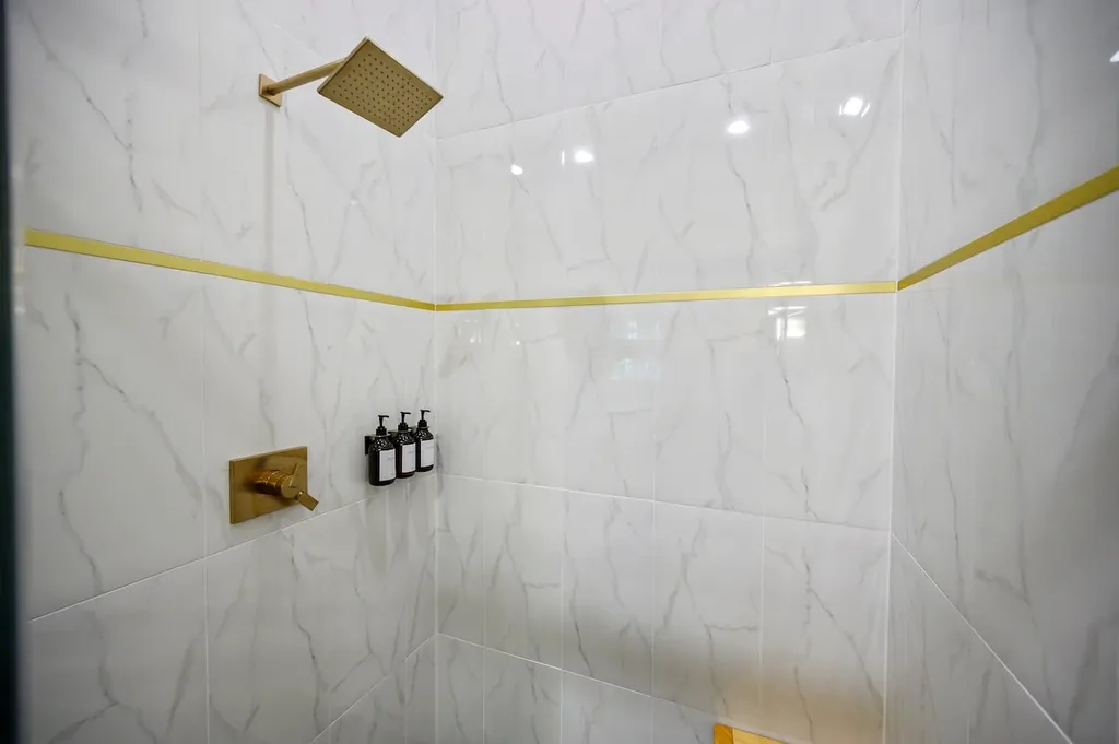 Full Bathroom 4 white tiled shower with gold fixtures