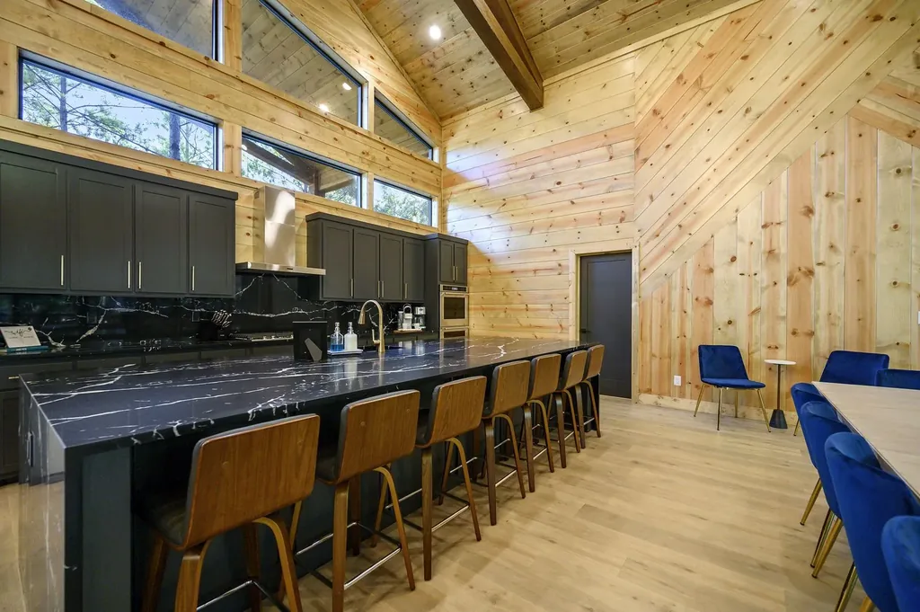 Kitchen bar at The Avalon with black marble countertops, dark cabinetry, and tan leather bar stools