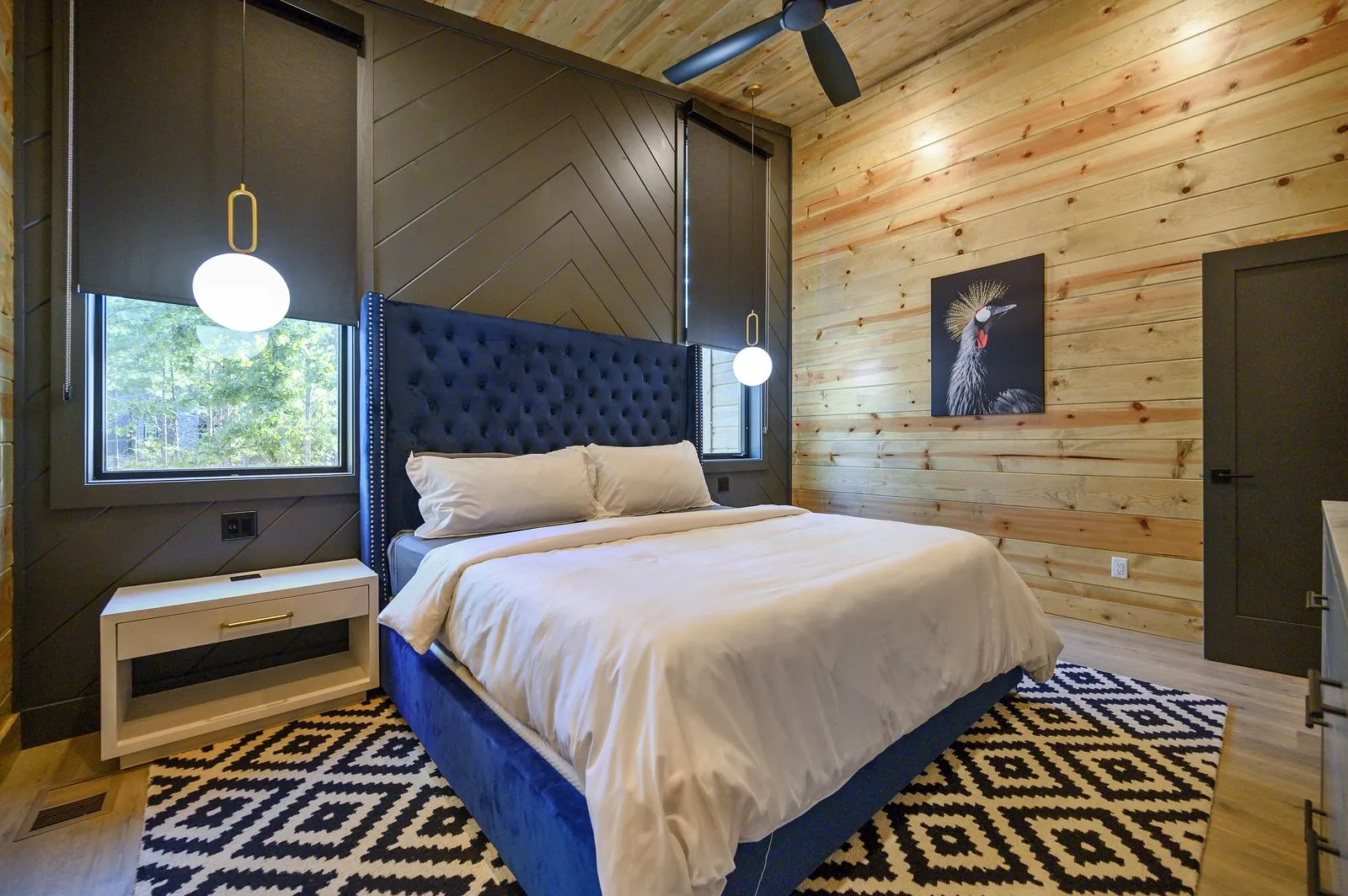 Bedroom at The Avalon with king bed, wall-mounted TV, dark accent wall, and tub-shower combo in view