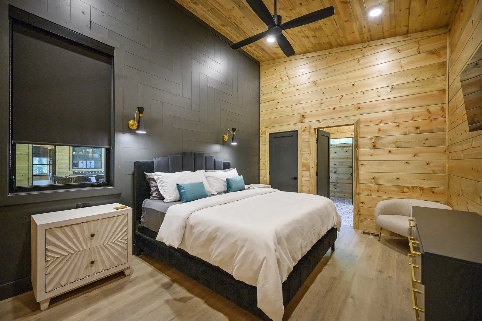Bedroom at The Avalon with navy tufted headboard, king bed, and forest views through side window