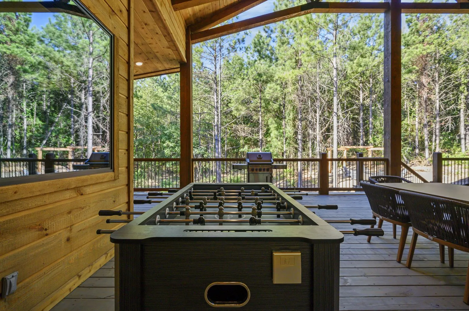 Covered outdoor seating area at The Avalon with gray lounge furniture and views into the forest