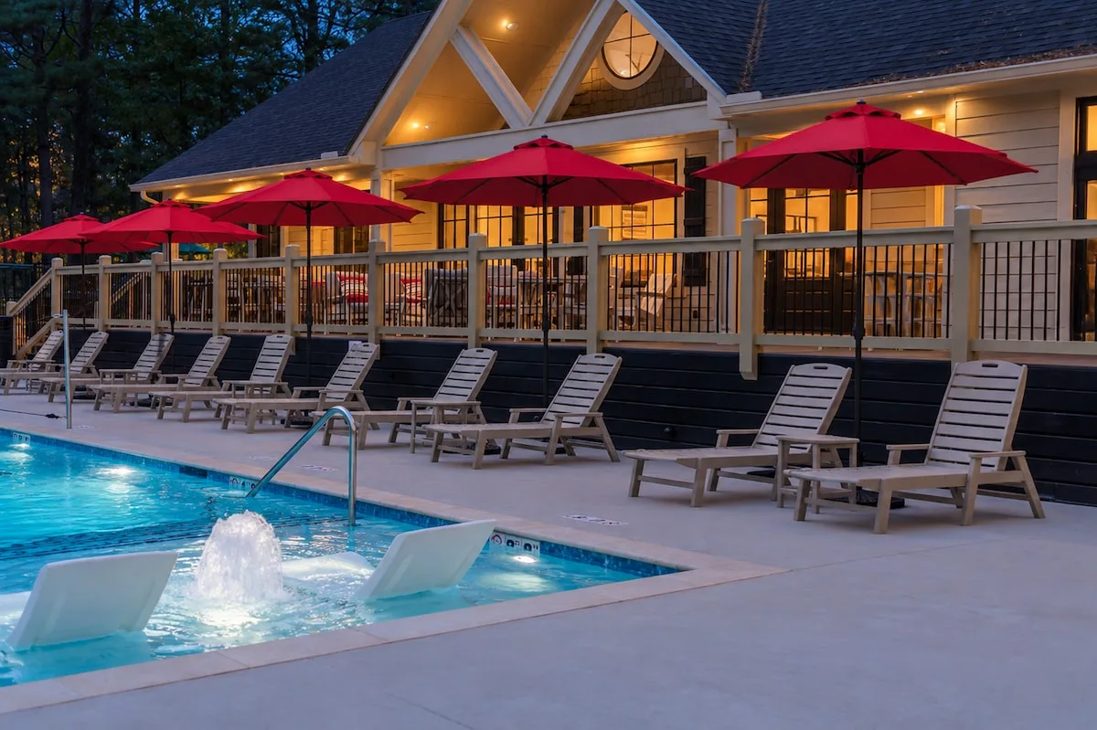 Shared Three Creeks Reserve pool with lounge chairs, red umbrellas, and clubhouse