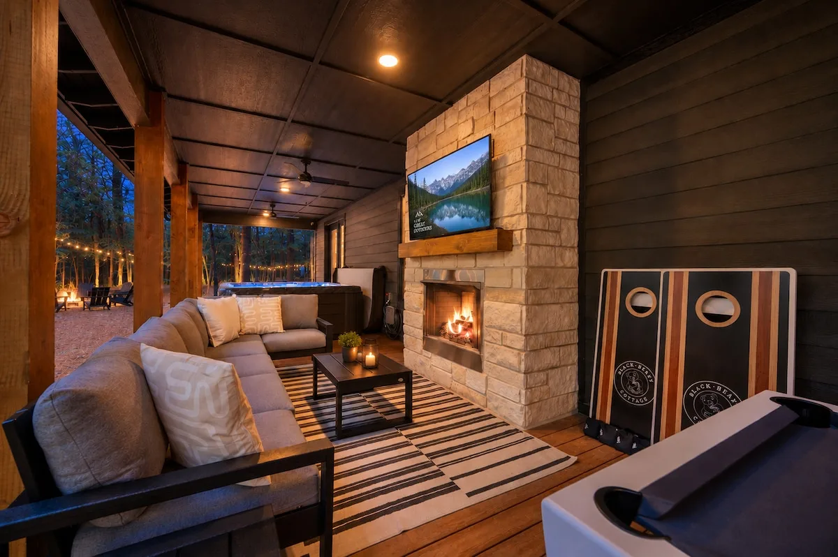 Covered outdoor living area with fireplace, TV, hot tub, and cornhole
