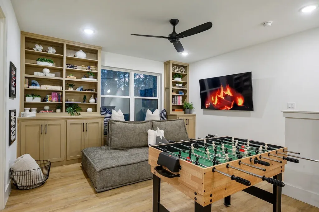 The Black-Beary — This game room features a foosball table, a wall-mounted TV, and built-in shelving with a window seat and lounge sofa.