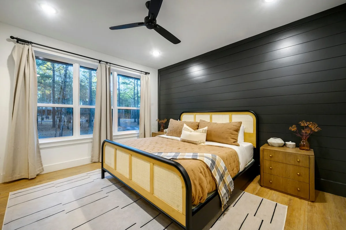 King bedroom with black shiplap wall and forest views