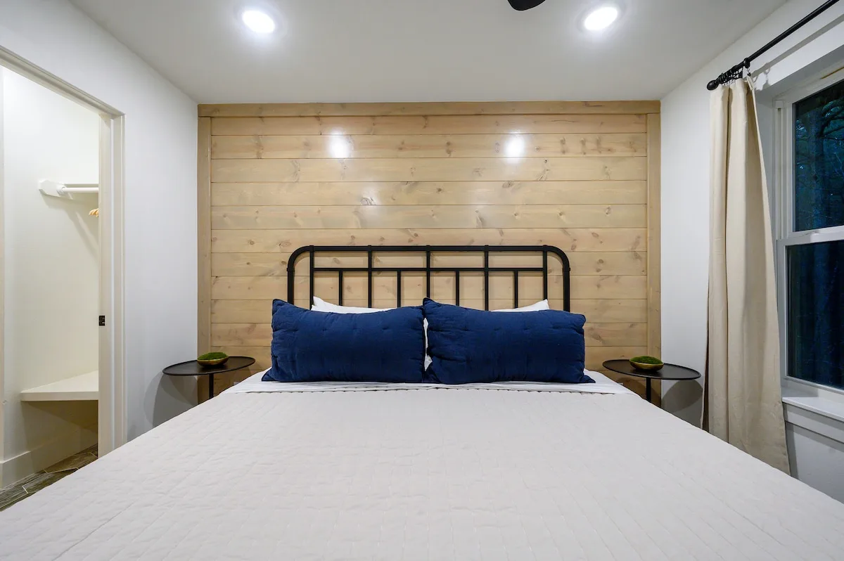 King bedroom with warm wood accent wall near its bathroom