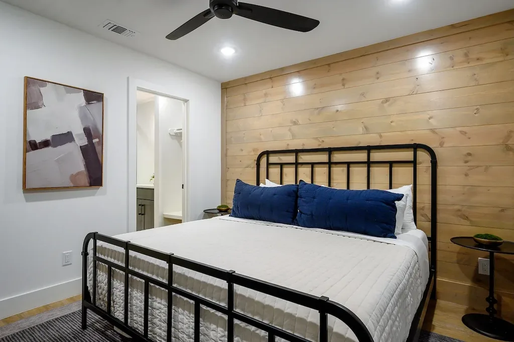 The Black-Beary — A black metal king bed and wood accent wall set a warm, modern tone in this bedroom with its own en suite bathroom.