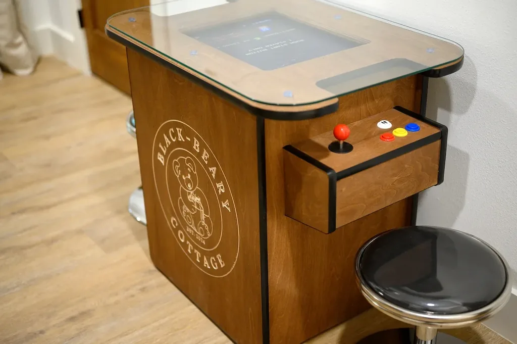 The Black-Beary — A tabletop arcade cabinet branded with the property's bear logo sits in the bedroom, with a joystick and button panel and a bar stool for play.