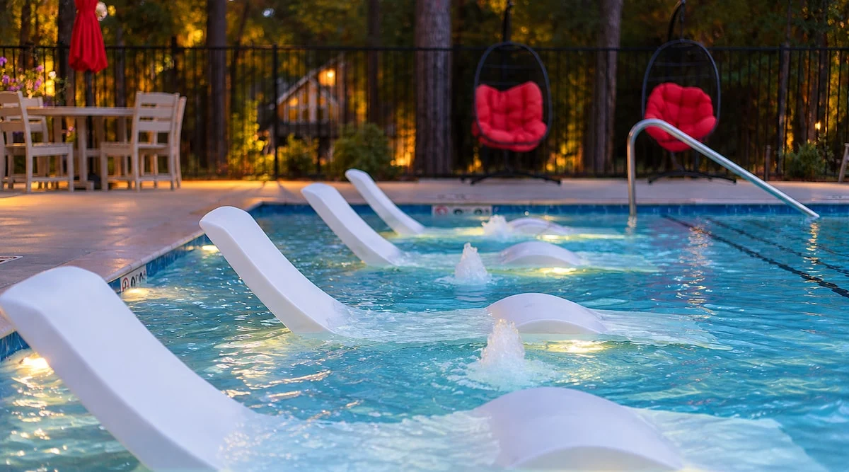 In-pool lounge chairs and a splash fountain sit in the resort-style pool at the Three Creeks Reserve clubhouse, included at no extra cost just across the street from the cabin.