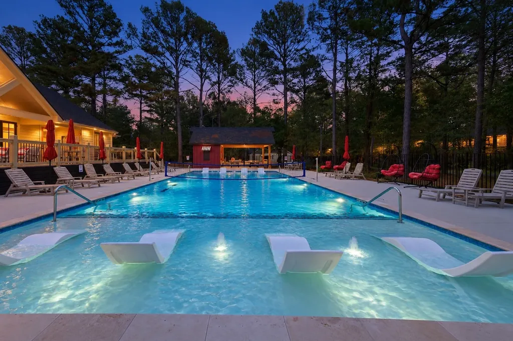 This is the Three Creeks Reserve community pool, a shared resort amenity included at no extra cost, with in-pool loungers, splash fountains, and a volleyball net, just across the street from the cabin.
