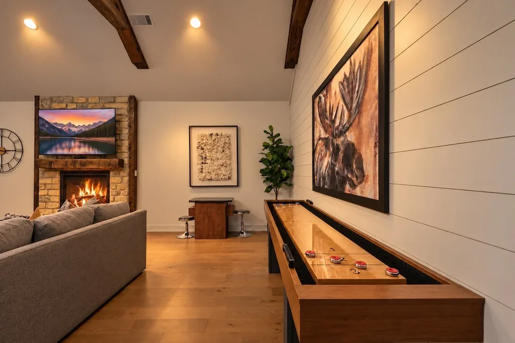 The private living area features a stone fireplace, smart TV, and a full-size shuffleboard table for game nights.