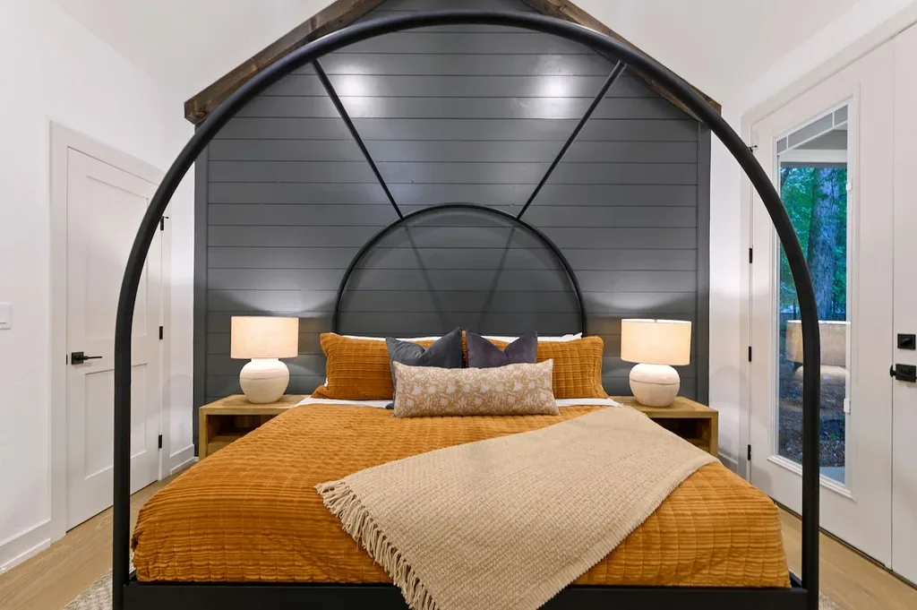 This king suite features an arched metal canopy bed and a private ensuite bathroom. A door opens directly onto the covered back patio.