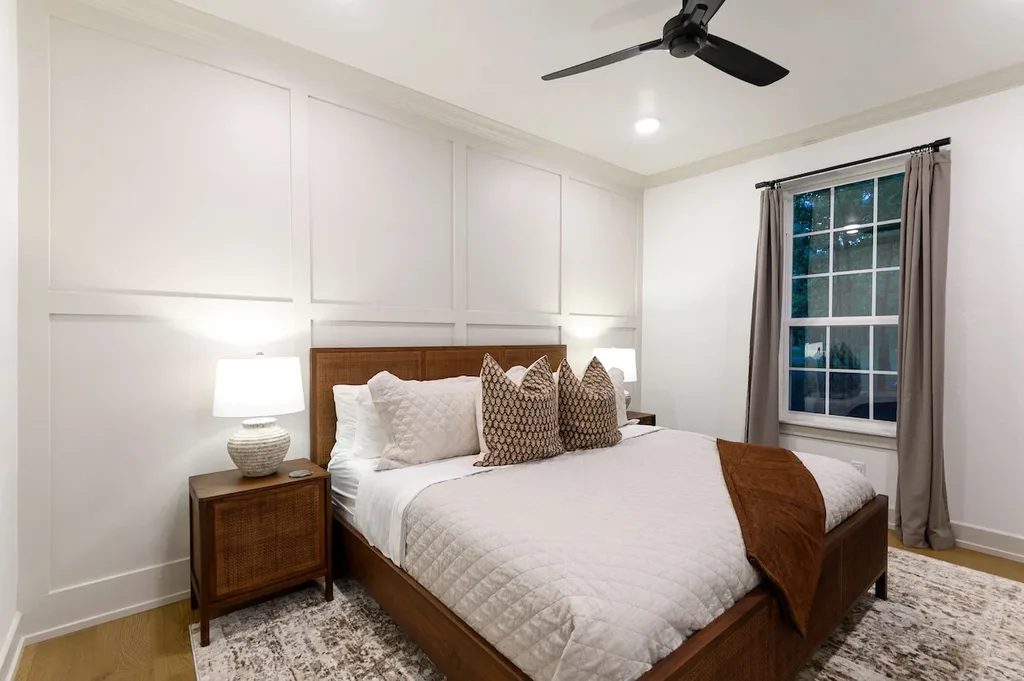 This king suite features a wood-framed bed, wainscoted accent wall, and a private ensuite bathroom.