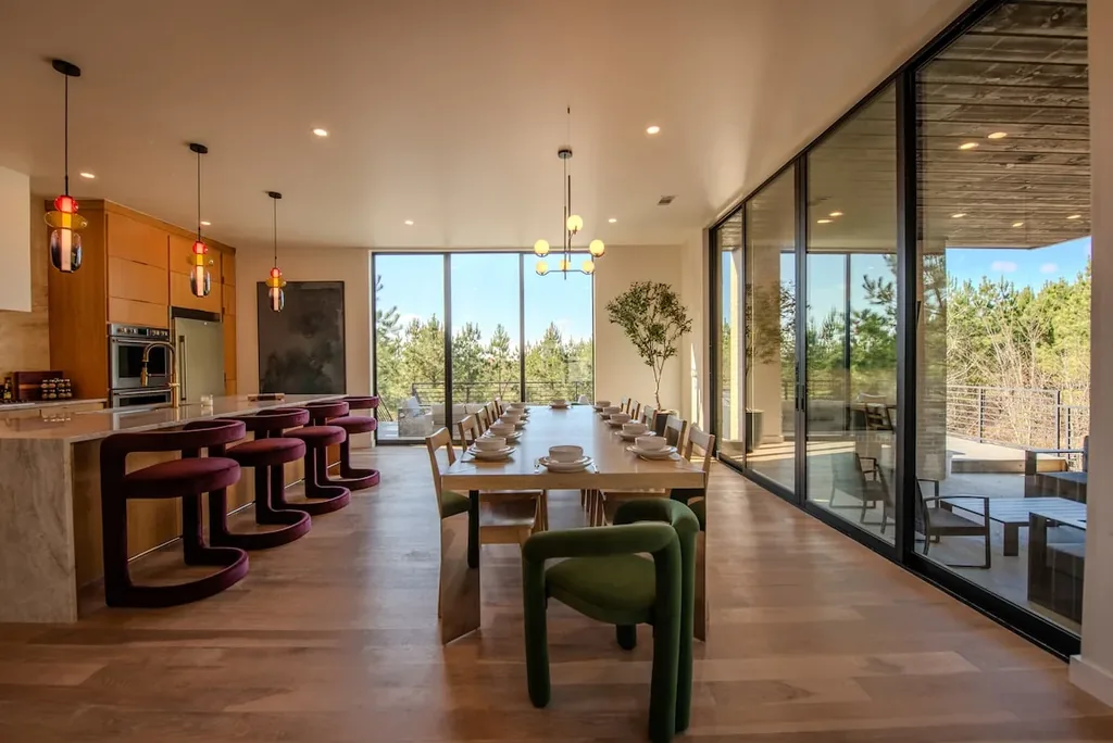 Dining table and kitchen bar beside floor-to-ceiling windows