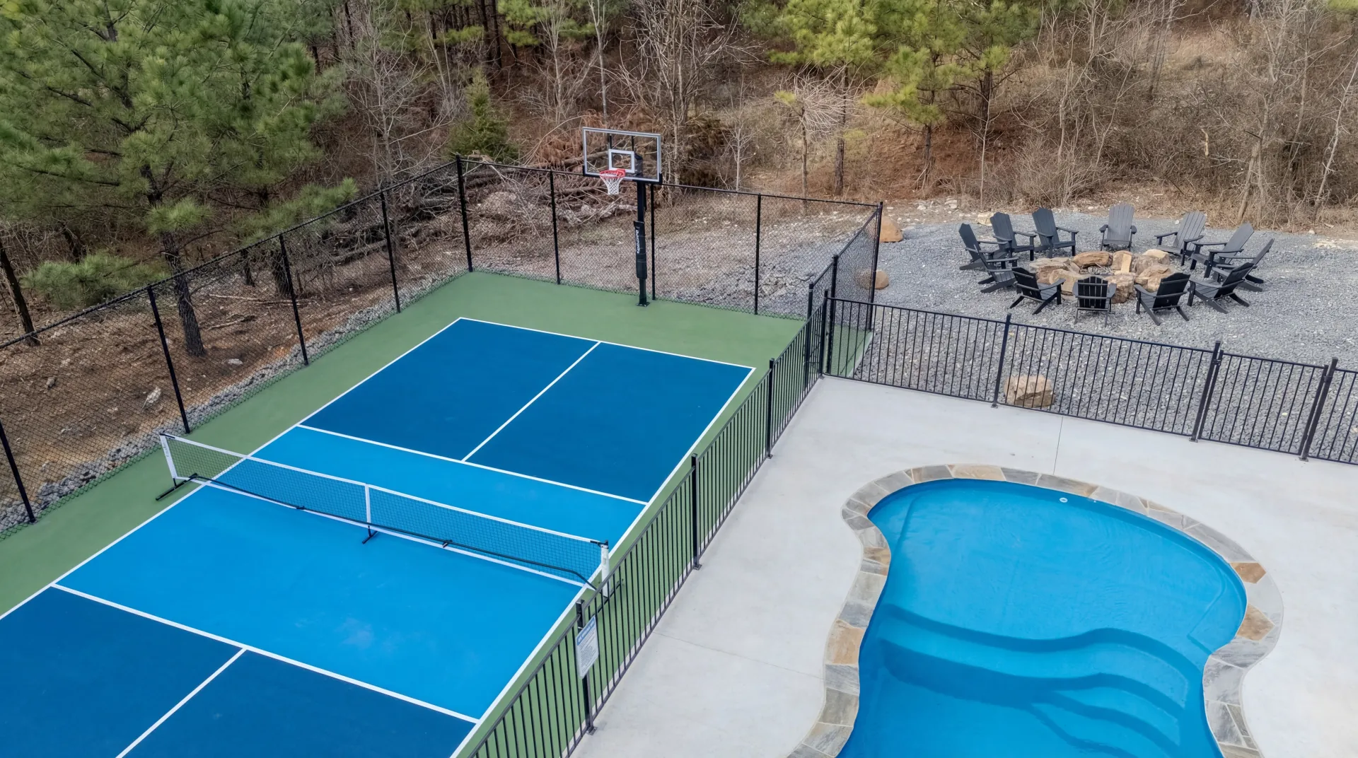 Private pickleball court at The Jade with adjacent heated pool, basketball hoop, and Broken Bow forest backdrop