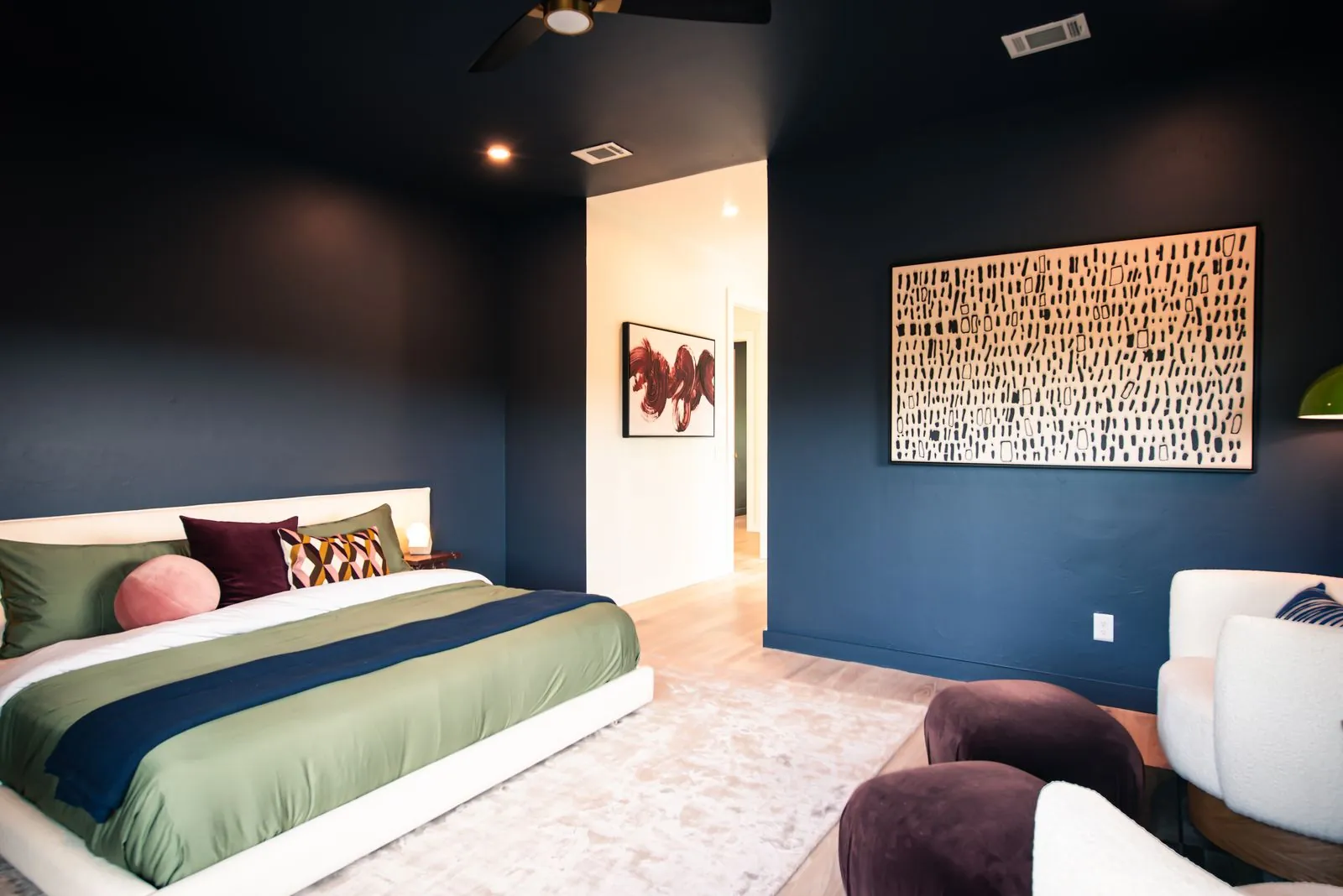 Moody dark blue bedroom at The Jade with king bed, abstract wall art, textured pillows, and ambient lighting