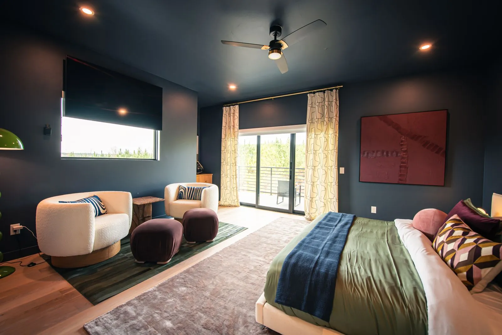 Bedroom lounge corner at The Jade with navy walls, modern swivel chair, accent pillow, and curated artwork