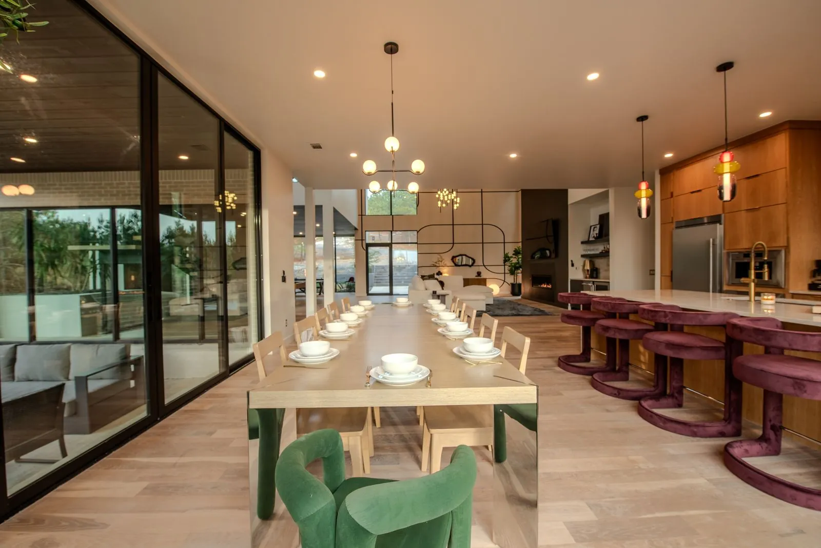 Open kitchen flowing into the dining area at The Jade with long table set for dinner and designer pendant lights