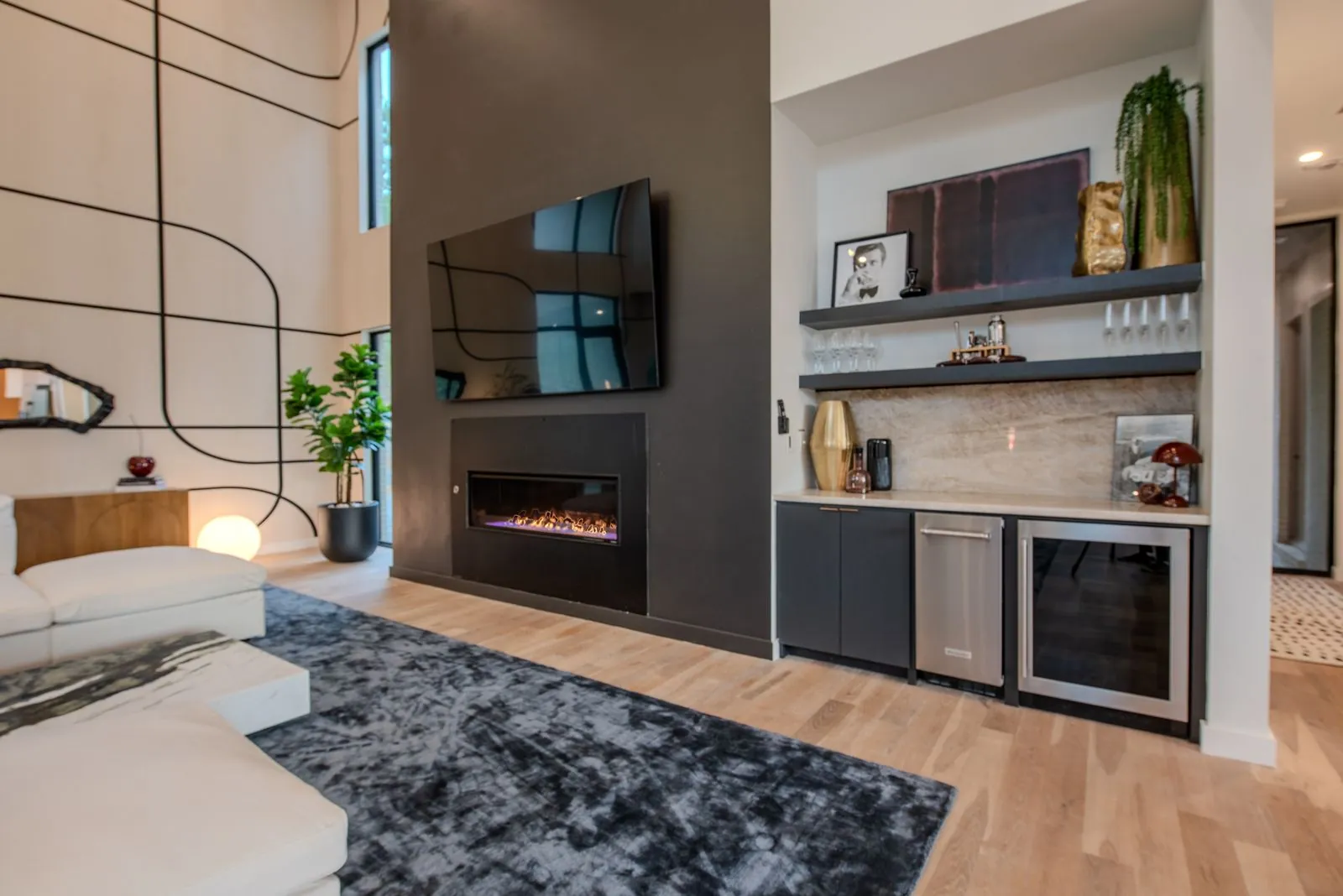 Entertainment wall in The Jade great room with mounted TV, built-in shelving, linear fireplace, and modern sculptural decor